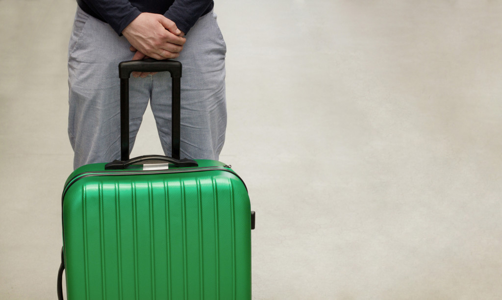A person with a green luggage being deported