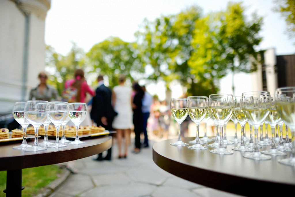 Wine glasses on a table during a wine-tasting event with guests in the background.