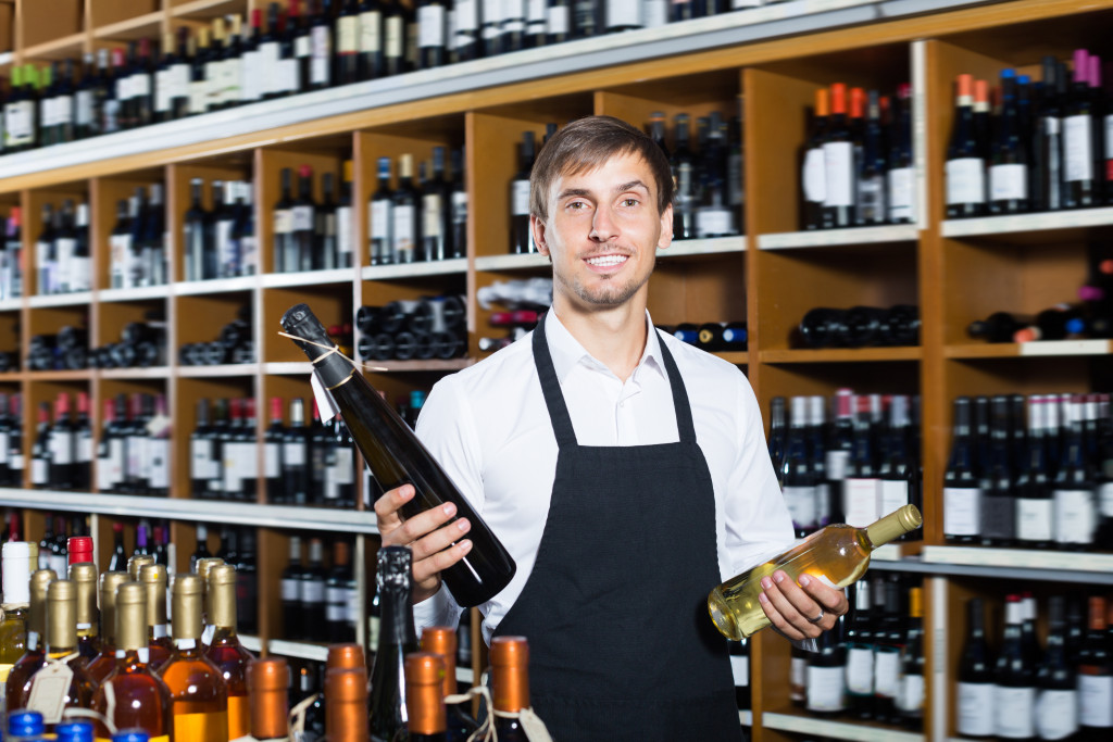 A man holding two bottles of wine in a stocked wine store