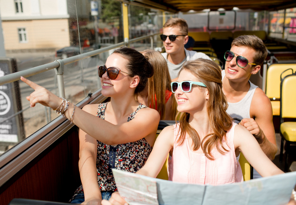 A group of people wearing sunglasses touring on a bus in the city
