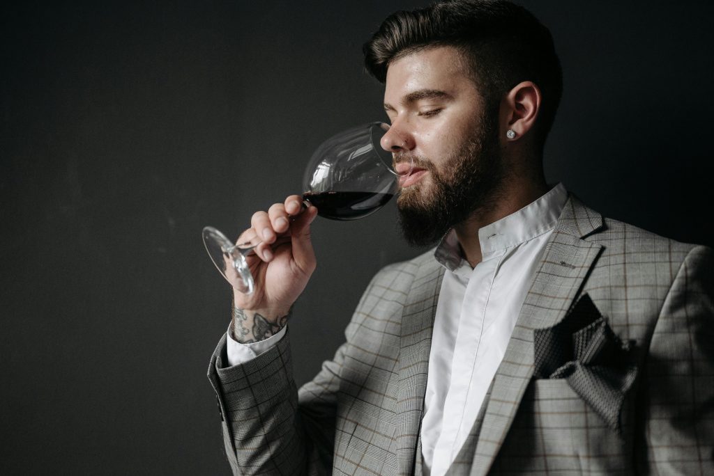 man in a checkered suit sipping wine