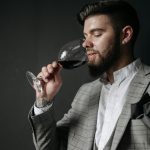 man in a checkered suit sipping wine